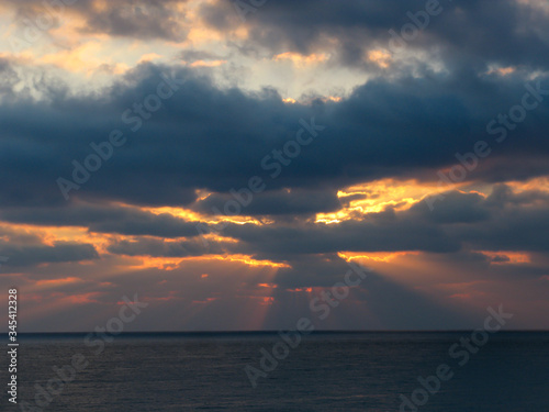 bright rays of the sun at dawn at sea through dark clouds