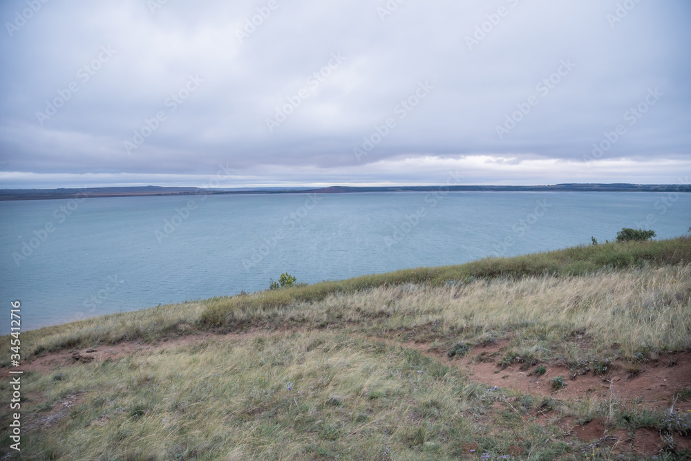 Aslykul - the largest lake in Bashkiria in cloudy weather with gray sky and blue water and a rocky shore Aslykul - the largest lake in Bashkiria in cloudy weather with gray sky and blue water and a rocky shore