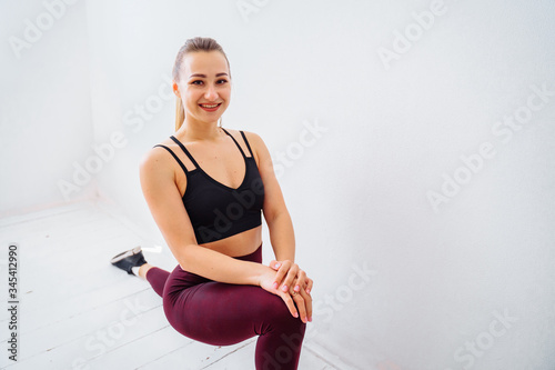 That's how it should be! Flexible, muscular, athlete girl does stretching, lifting leg up to the wall. Fitness trainer making a twine at home in the bedroom. Conducting live broadcasts for students
