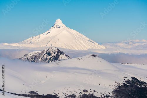 Snowy mountainous landscape, in the middle of the winter season, with the Puntiagudo volcano in the background surrounded by clouds