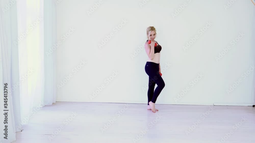 Beautiful blonde woman engages in fitness with dumbbells in sports hall Beautiful blonde woman engages in fitness with dumbbells in sports hall