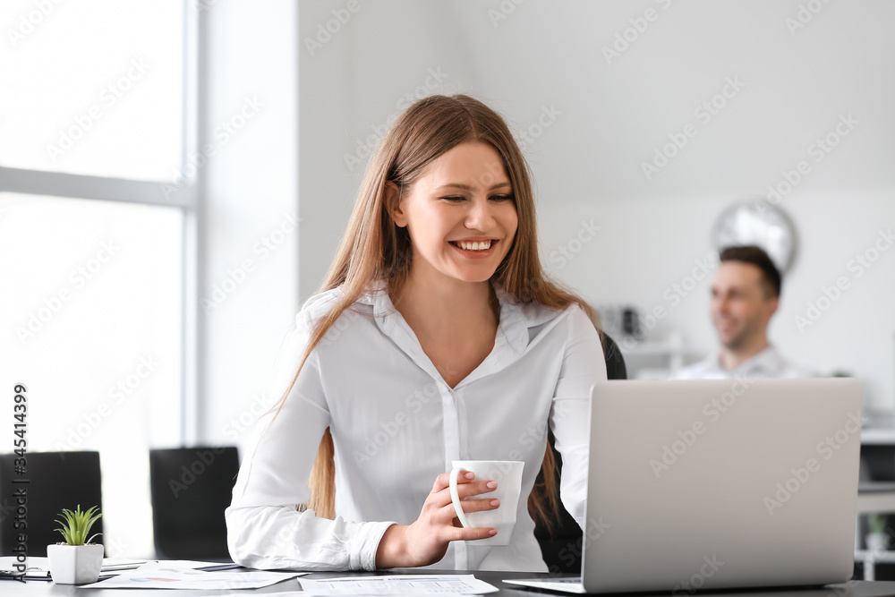 Young woman drinking coffee while working in office Young woman drinking coffee while working in office