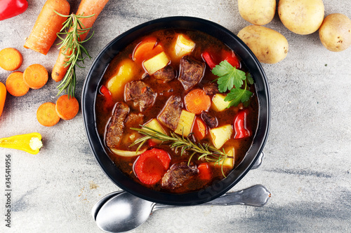 Meat stew with vegetables. Beef stew with potatoes, carrots and fresh herbs on table.