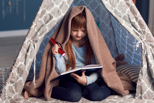 Little girl reading book in...