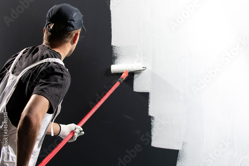 Male decorator painting a wall photo