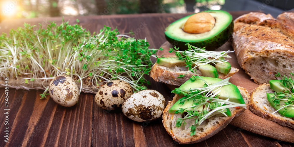 sandwiches with avocado and microgreens, quail eggs on a wooden background. healthy diet. serving option. the process of making breakfast. sandwiches with avocado and microgreens, quail eggs on a wooden background. healthy diet. serving option. the process of making breakfast.