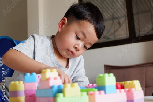 Close up of child's hands playing with colorful plastic bricks at the table. Toddler having fun and building out of bright constructor bricks. Early learning. stripe background. Developing toys