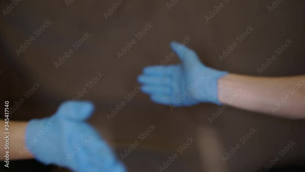 two hands of two people in blue rubber gloves shake each other two hands of two people in blue rubber gloves shake each other
