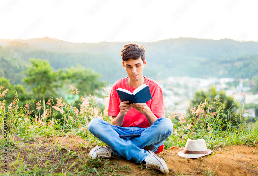 Person reading a book with mountains in the background