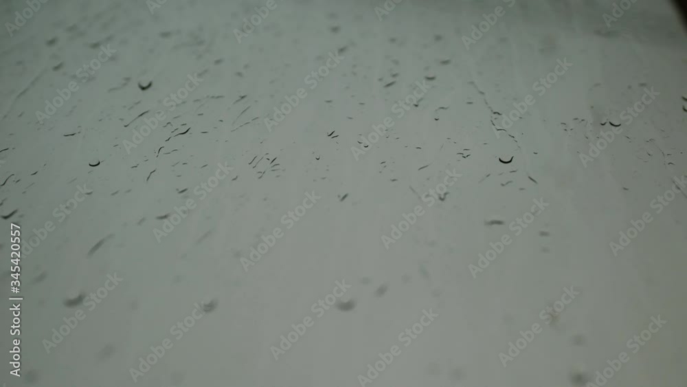 Close up drops of rain flow down the glass against a gray sky. There is a downpour on the street. UltraHD 4k video background. Close up drops of rain flow down the glass against a gray sky. There is a downpour on the street. UltraHD 4k video background.