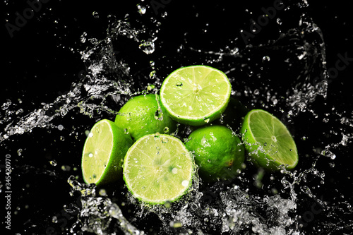 Fresh limes with water splashes on dark background