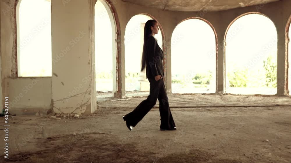 slow motion side view woman in pantsuit walking in abandoned classic building slow motion side view woman in pantsuit walking in abandoned classic building