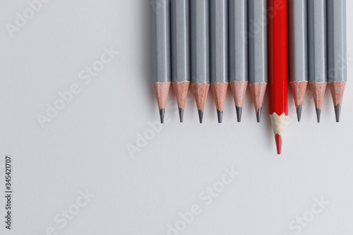 red pencil and gray pencils on a white paper background.
