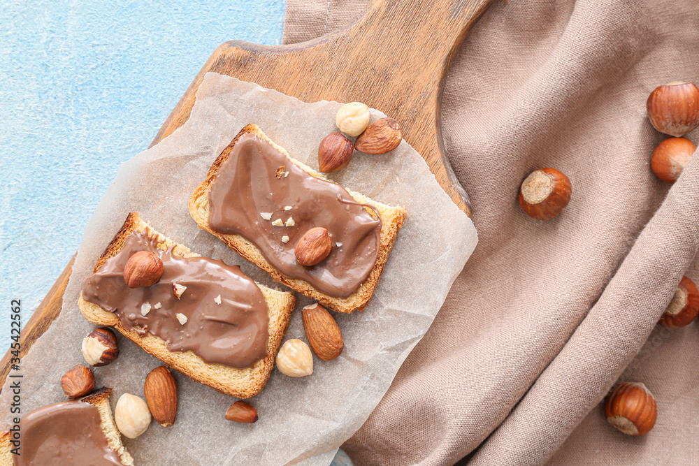 Board with fresh bread and chocolate paste on color background Board with fresh bread and chocolate paste on color background