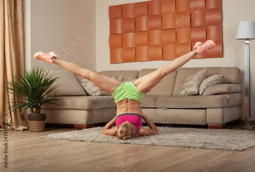 young blonde sporty fit woman doing gymnastic and yoga exercis at home training