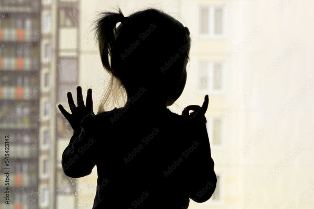 Girl looks out the window against the background of apartment building concept stayathome