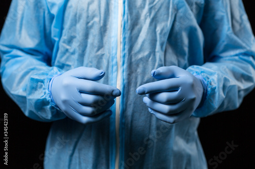 male hands in medical disposable gloves and overalls chemical protection blue, close-up © Mira