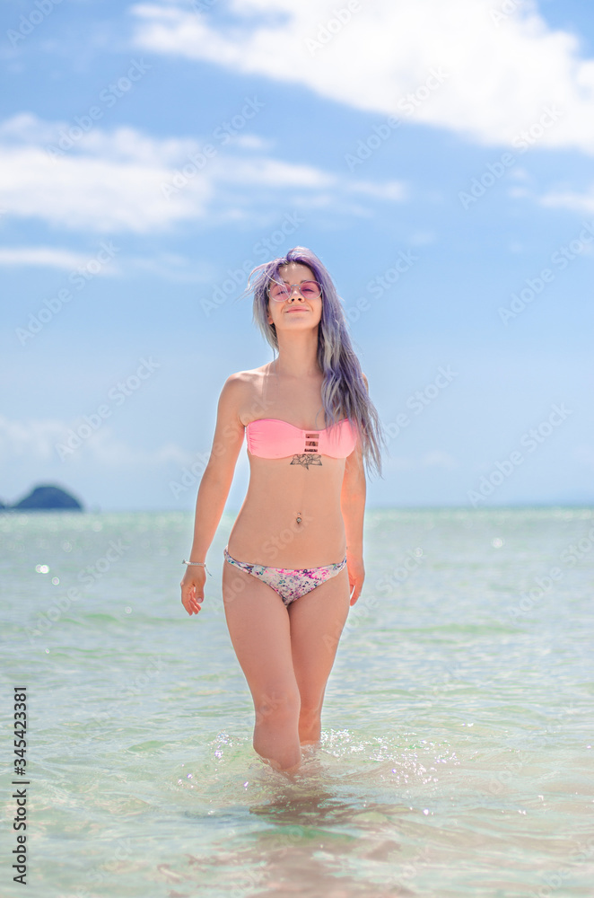 beautiful girl on a paradise green island. Slender girl on the beach. Girl with purple hair in a swimsuit. Happy girl on vacation. A woman with a beautiful slim body on the beach in a swimsuit. Sexy