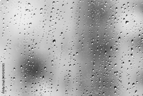 Autumn day. Window of a residential building in an apartment. Horizontal frame. Rain drops on the windows. Soft focus. Black and white image, soft contrast.