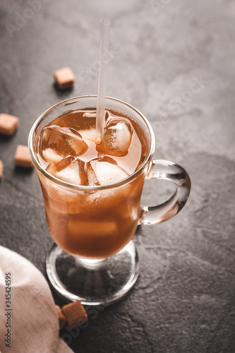 Cup of tasty iced coffee on dark background