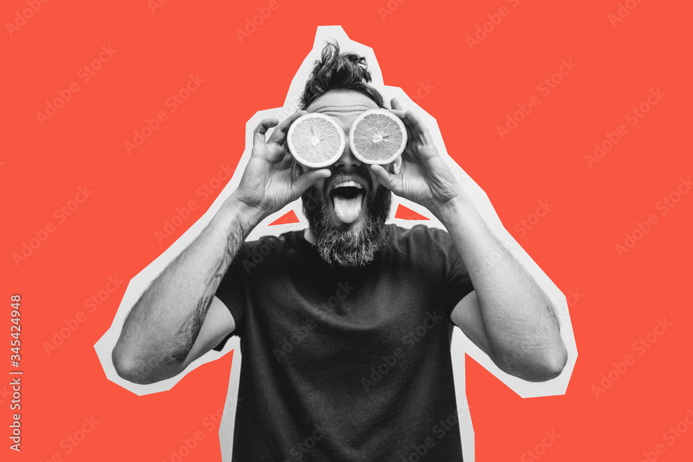 Young bearded hipster man holding slices of orange in front of his eyes. Crazy emotions Young bearded hipster man holding slices of orange in front of his eyes. Crazy emotions