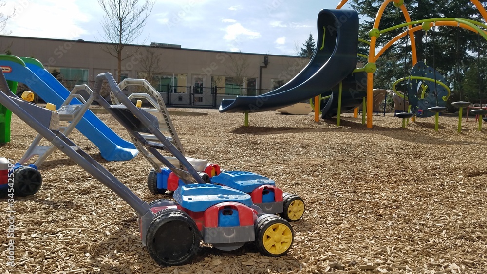 Children push car toys laying on an empty playground
