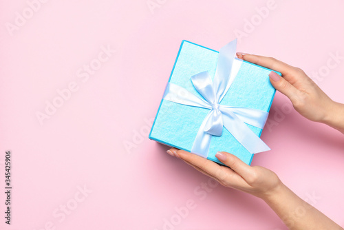 Female hands with gift on color background
