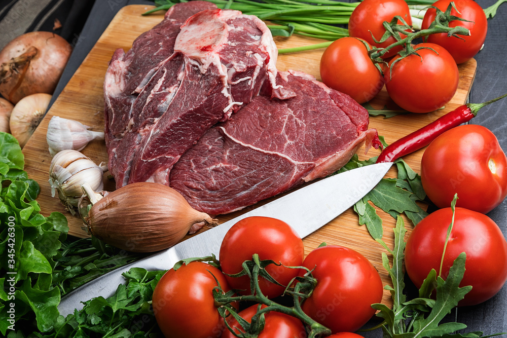 a piece of fresh choice beef lies on a wooden chopping Board. Fresh meat and vegetables Juicy steak with greens. Proper, balanced nutrition. a piece of fresh choice beef lies on a wooden chopping Board. Fresh meat and vegetables Juicy steak with greens. Proper, balanced nutrition.