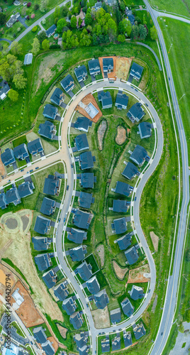 High resolution aerial picture of a new American residential real estate development forming an oval shape with curving street single family houses and empty home sites