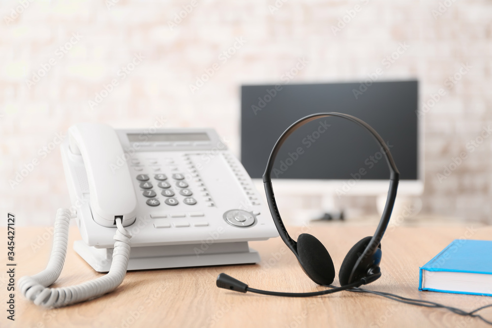 Headset and telephone on table of technical support agent in office Headset and telephone on table of technical support agent in office