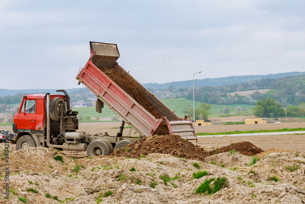 Fototapeta premium Dump truck unloading soil at construction site.