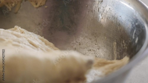 Stirring homemade bread dough in a metal bowl. A home baker stirs raw sourdough batter with a wooden spoon forming gluten. Baking bread during the 2020 lockdown is the current trending hobby.