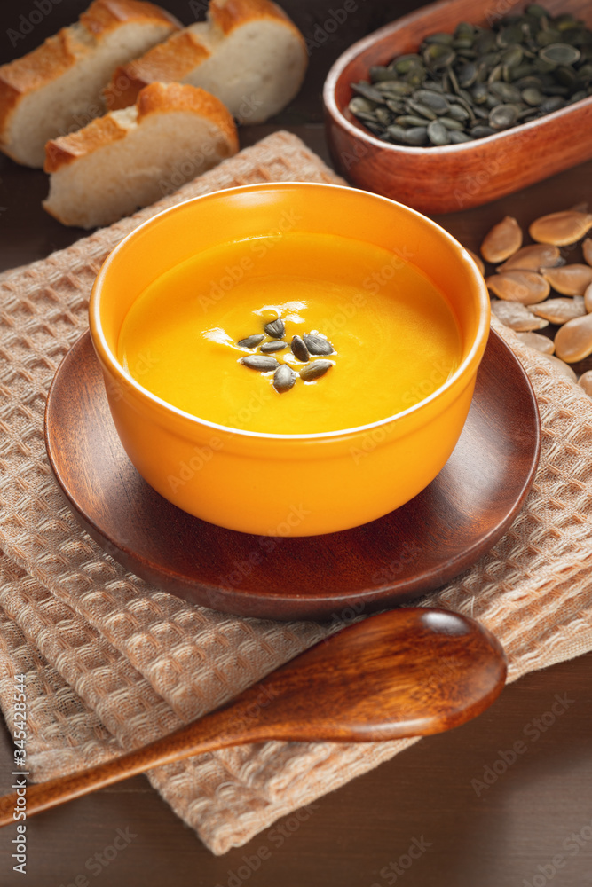 Roasted pumpkin and carrot soup with cream and pumpkin seeds on a wooden table.. Roasted pumpkin and carrot soup with cream and pumpkin seeds on a wooden table..