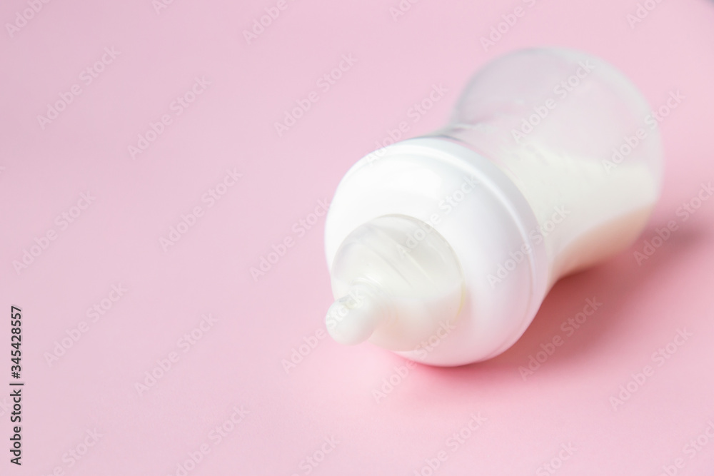 Baby milk bottle on a pink background with neagtive space. Baby milk bottle on a pink background with neagtive space.