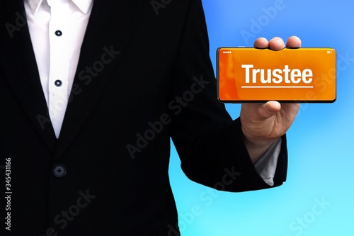 Trustee. Lawyer in a suit holds a smartphone at the camera. The term Trustee is on the phone. Concept for law, justice, judgement