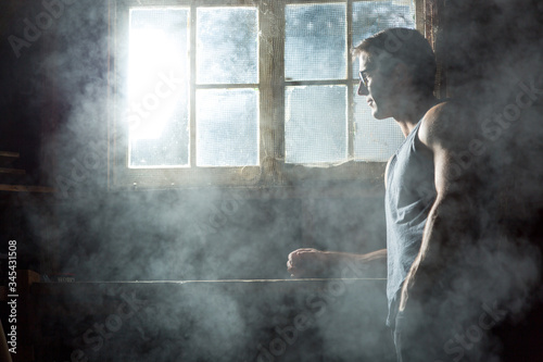 man looking out of mysterious window in smoky room