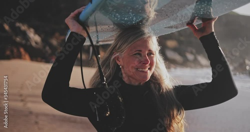 Close up senior woman running with surfboard at the beach