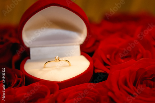 Wedding ring in a gift box on a bouquet of red roses. © Александр Бутылов