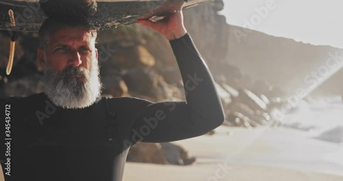 Close up senior handsome man carrying surfboard at the beach