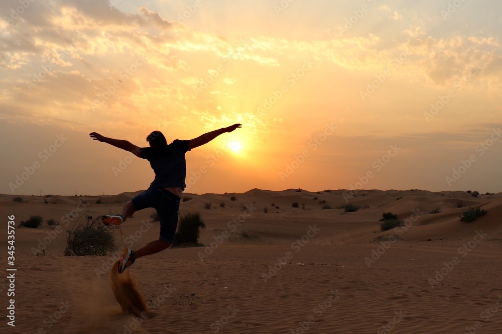 happy young man jumping on the beach at sunset