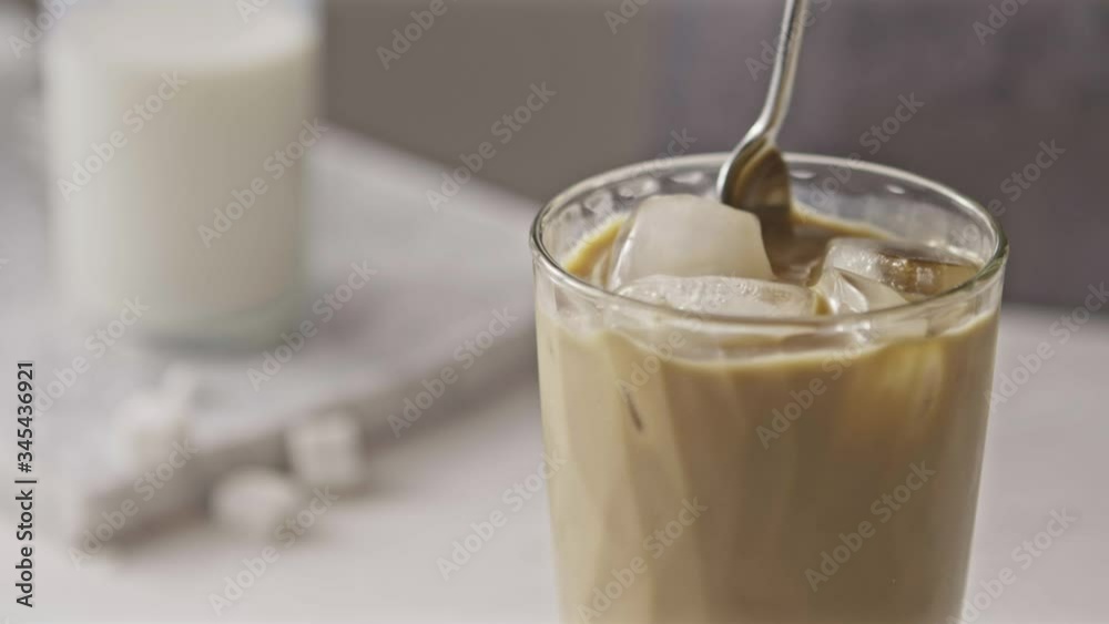 Freshly prepared cold coffee ice cocktail with milk mixing by spoon. Freshly prepared cold coffee ice cocktail with milk mixing by spoon.