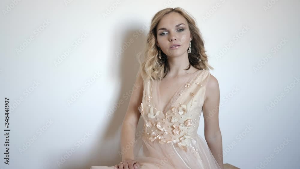 young woman in a beige wedding dress posing on wall background, closeup portrait