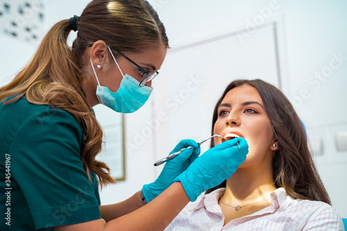 Closeup shot professional dentist with protective surgical mask  doing check up of patient 