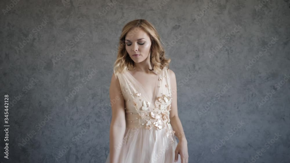 beautiful young woman in a beige wedding dress posing on wall background beautiful young woman in a beige wedding dress posing on wall background
