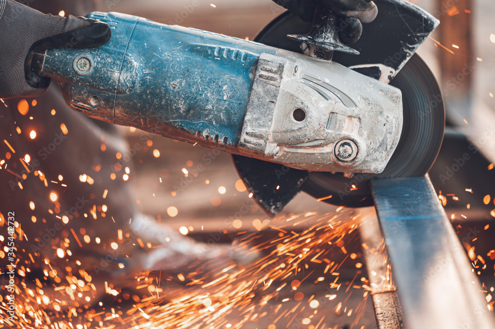 Construction worker using Angle Grinder cutting Metal at construction site .