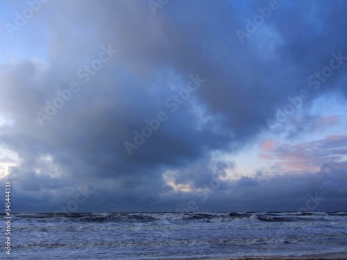 North Sea beach in Kijkduin  the Netherlands  sunset time  dramatic clouds  subtle red clouds  rain clouds  rough sea  dutch weather 