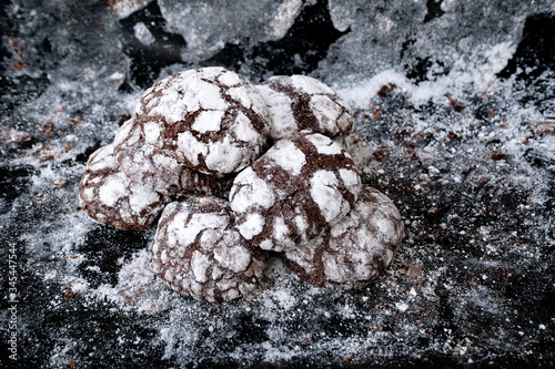 Freshly baked sweet chocolate cookies at baking sheet. Cookies sprinkled with powdered sugar on a textured background. Home cooking