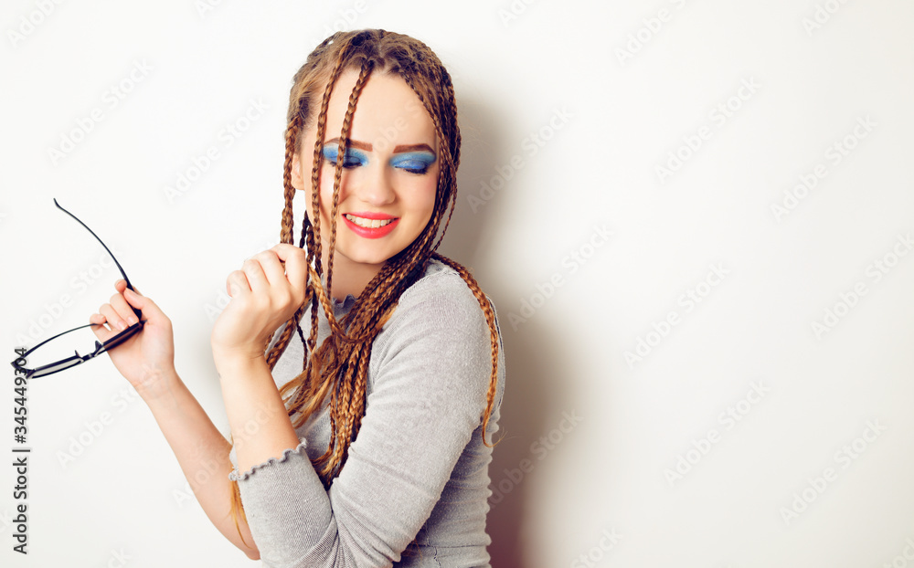 Girl with dreadlocks, pigtails dancing, model in the style of the 80s. 90s, with bright blue make-up. DJ girl on a white background posing. Drive photo of the model in the old style. Girl with dreadlocks, pigtails dancing, model in the style of the 80s. 90s, with bright blue make-up. DJ girl on a white background posing. Drive photo of the model in the old style.