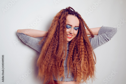 Girl with curled voluminous hair, model with hairstyle in the style of the 80s. 90s, with bright blue make-up. Hair care, brunette red-haired girl with long hair, curling curls, corrugation hair