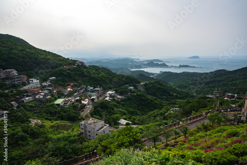 Scenic Panoramic View of Village sitting on the side of a mountain during cloudy weather with a view of distant islands 